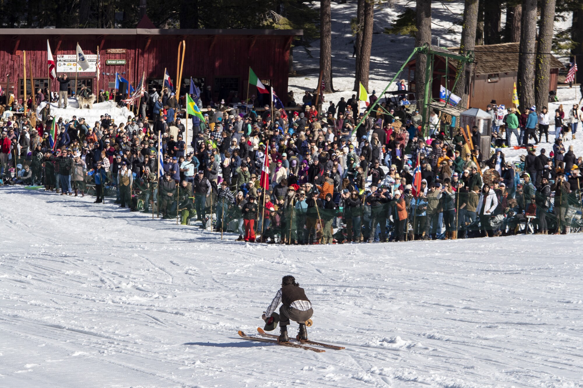 A crowd of spectators watch a ski racer