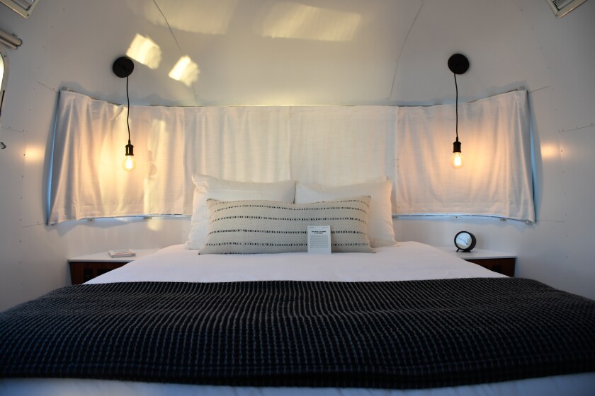 A bed flanked by Edison bulb sconces in an Airstream.