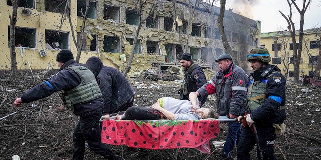 Ukrainian emergency employees and volunteers carry an injured pregnant woman from a maternity hospital damaged by shelling in Mariupol, Ukraine, Wednesday, March 9, 2022. 