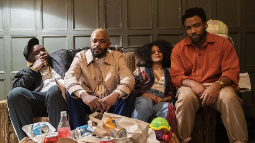 Three men and one woman sit on a couch. Empty cans and food takeout containers are on a table in front of them 