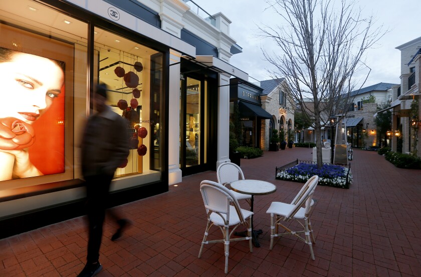 A man walks in an outdoor shopping center .