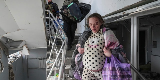 An injured pregnant woman walks downstairs in the damaged by shelling maternity hospital in Mariupol, Ukraine.