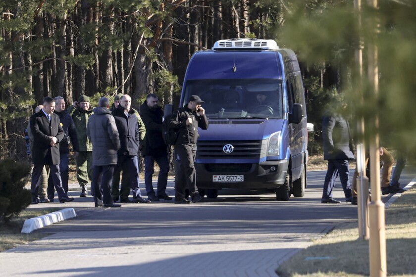 The Russian delegation leaves a bus while trees are in the background.