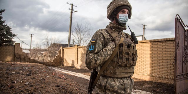 A Ukrainian soldier passes by houses in the village of Novoluhanske, Luhansk region, Ukraine.