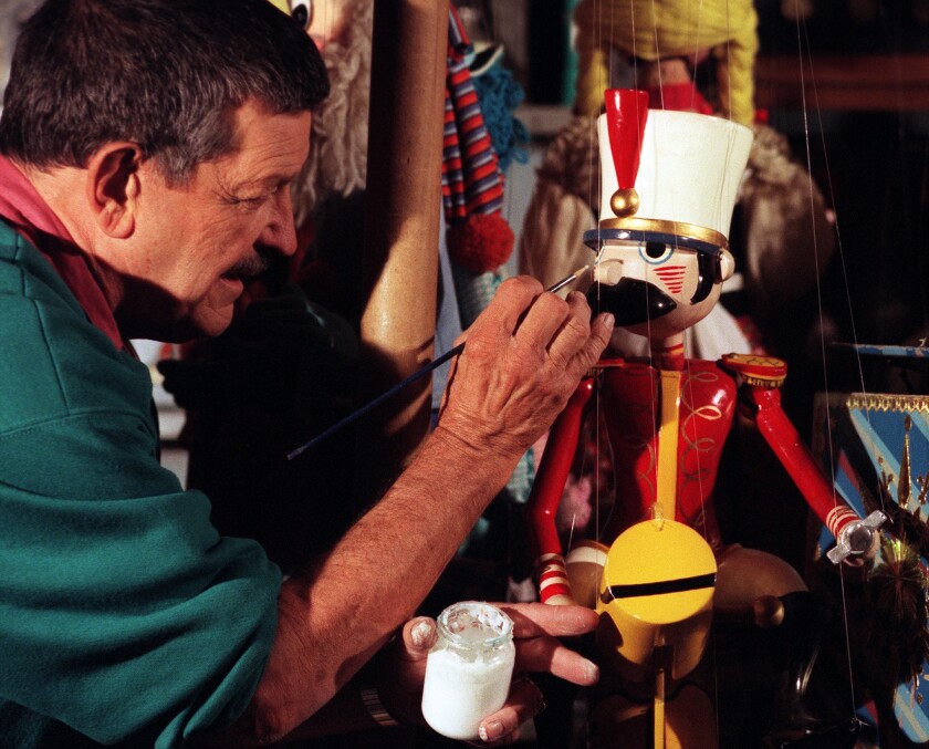 A man repairs a drum major marionette.