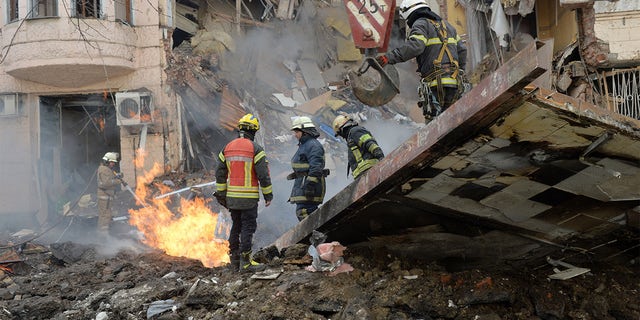 Firefighters work to clear the rubble and extinguish a fire after a Russian rocket exploded in Kharkiv, Ukraine, March 14, 2022.