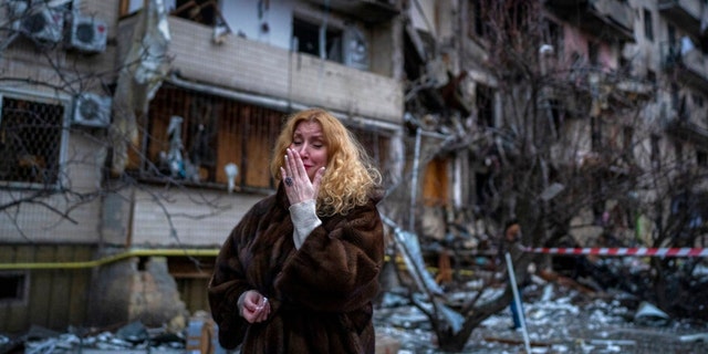 Natali Sevriukova reacts next to her house following a rocket attack the city of Kyiv, Ukraine, Friday, Feb. 25, 2022.