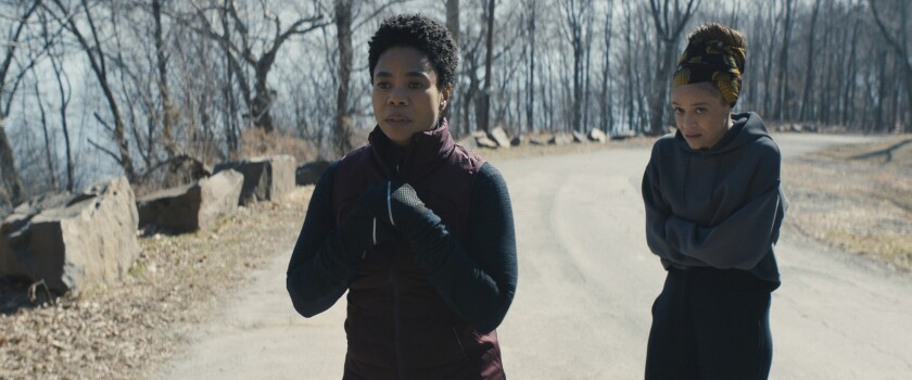 Two women in workout clothes shiver on a road  