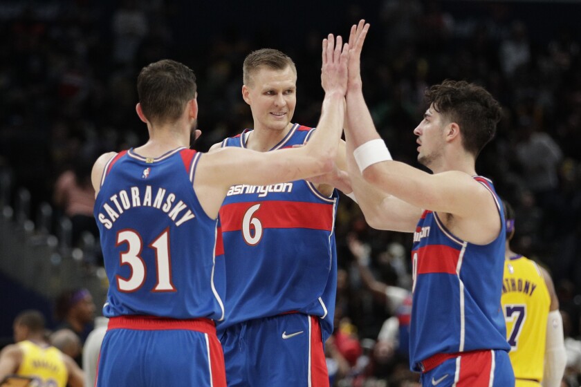 The Wizards' Kristaps Porzingis (6), Tomas Satoransky (31) and Deni Avdija, right, celebrate March 19, 2022.