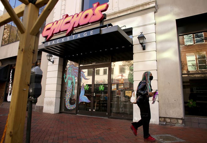 A person walks by Chicho’s Pizza Backstage, in Norfolk, Va., Saturday, March 19, 2022, where a fatal shooting took place outside the restaurant and bar earlier in the day. Newspaper reporter Sierra Jenkins was one of the people killed during the shooting after getting caught in the crossfire.