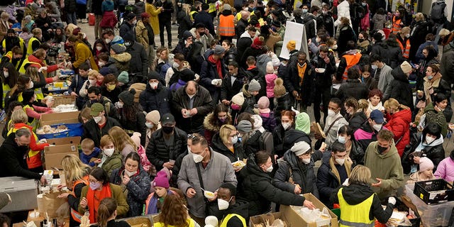 Ukrainian refugees queue for food in the welcome area after their arrival at the main train station in Berlin