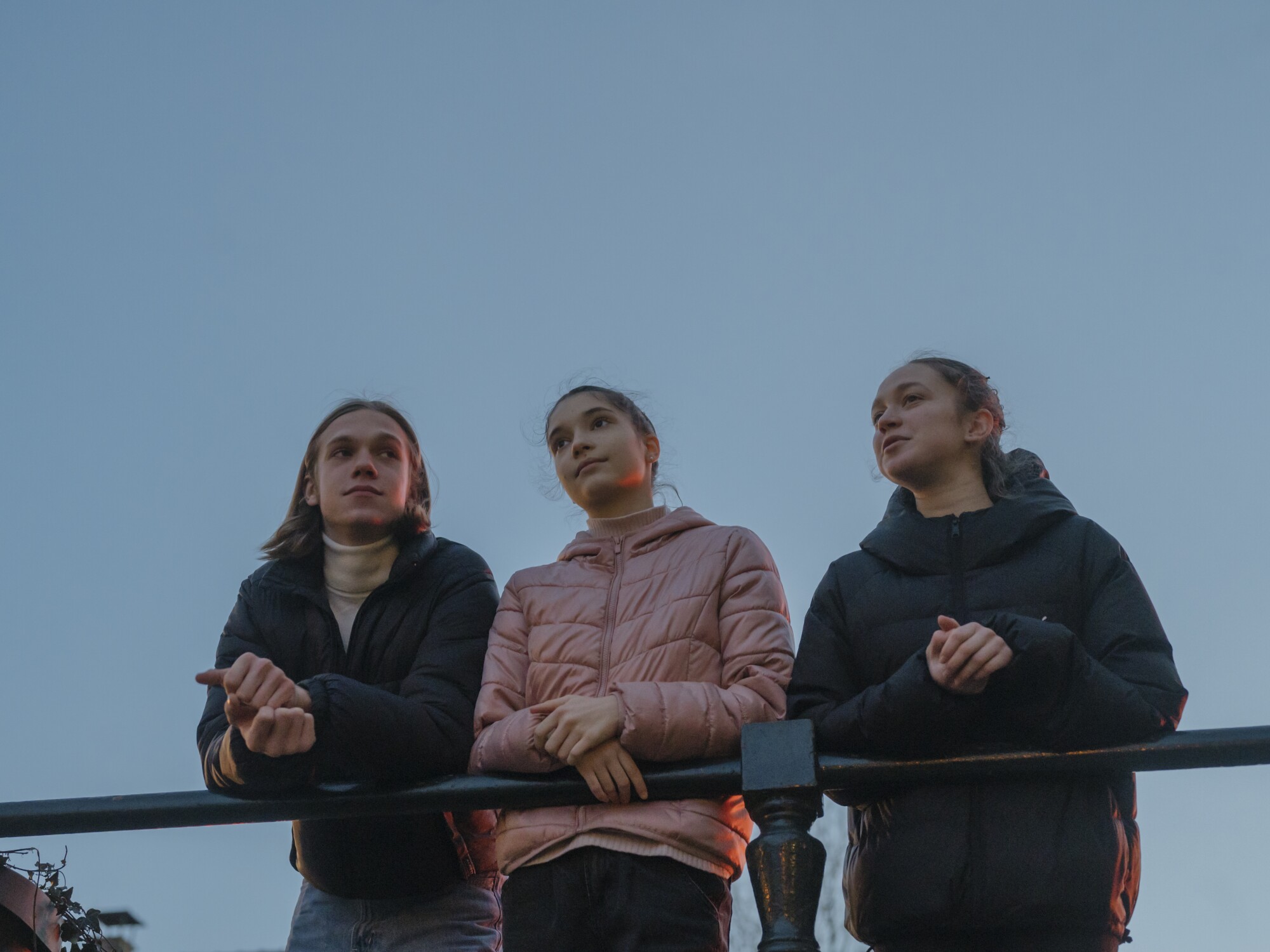 A boy, left, and two lean on a railing 