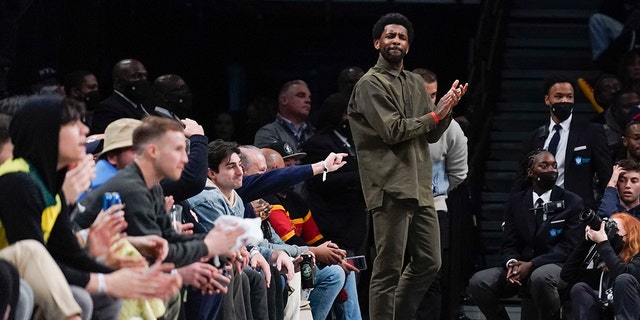 Brooklyn Nets' Kyrie Irving watches the game from his seats during the second half of the NBA basketball game between the Brooklyn Nets and the New York Knicks at the Barclays Center, Sunday, Mar. 13, 2022, in New York. The Nets defeated the Knicks 110-107. 