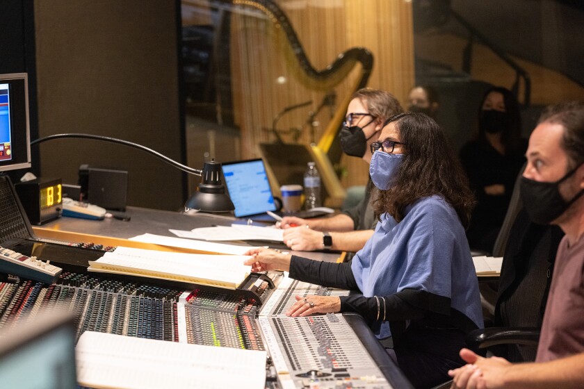 People wearing face masks working behind a large mixing console.