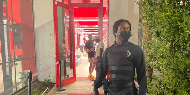 An armed guard stands watch outside a high-end boutique sneaker store on Collins Avenue in Miami Beach Wednesday.