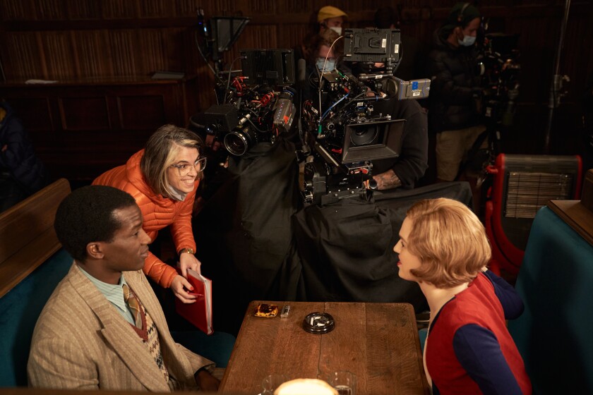 A woman directs two actors on the set of a movie.