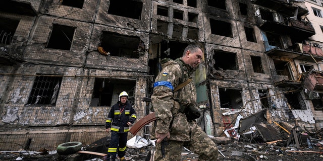 Ukrainian soldiers and firefighters search in a destroyed building after a bombing attack in Kyiv, Ukraine, Monday, March 14, 2022. 