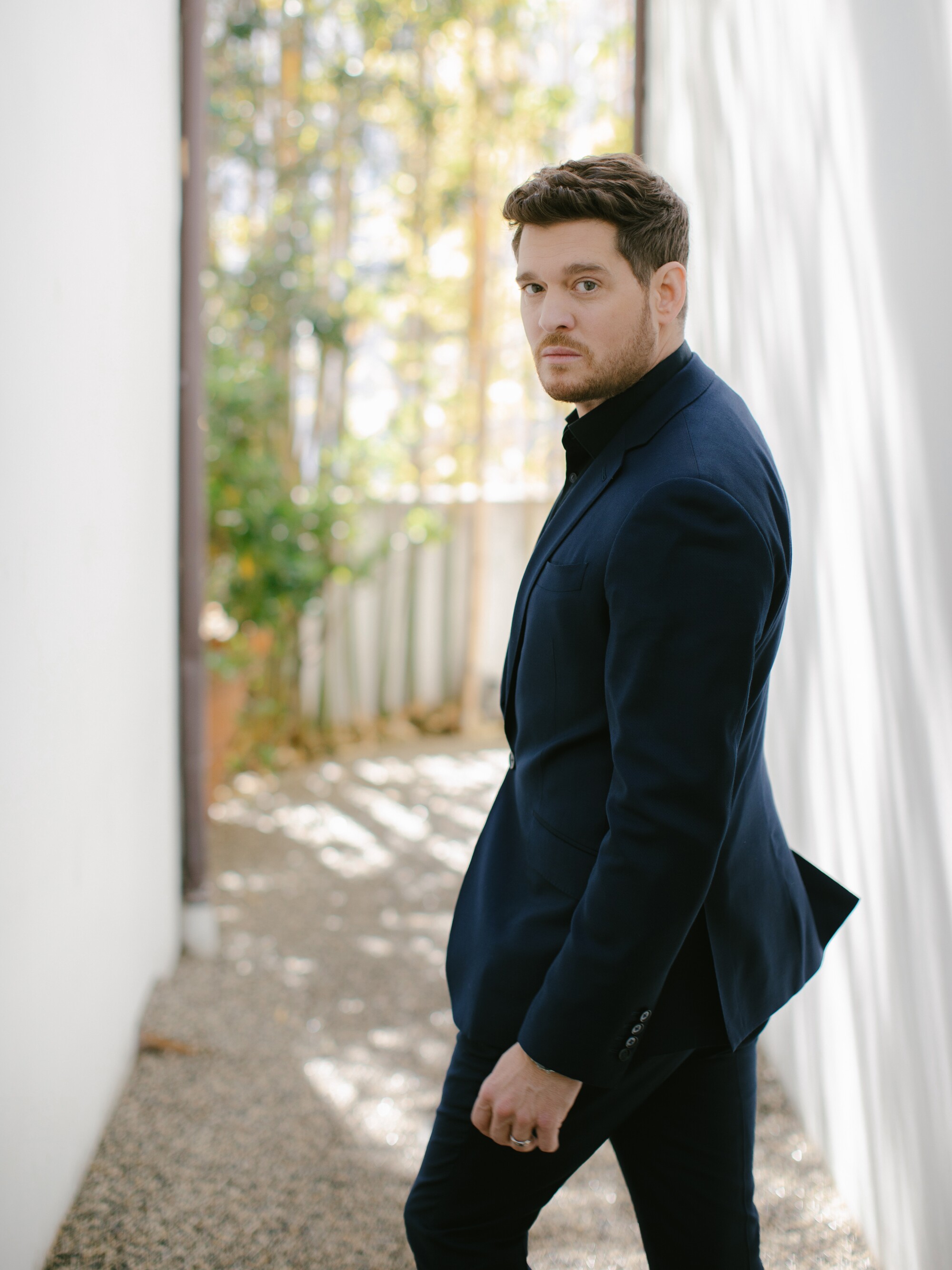 A man in a blue suit looks over his shoulder in an alleyway