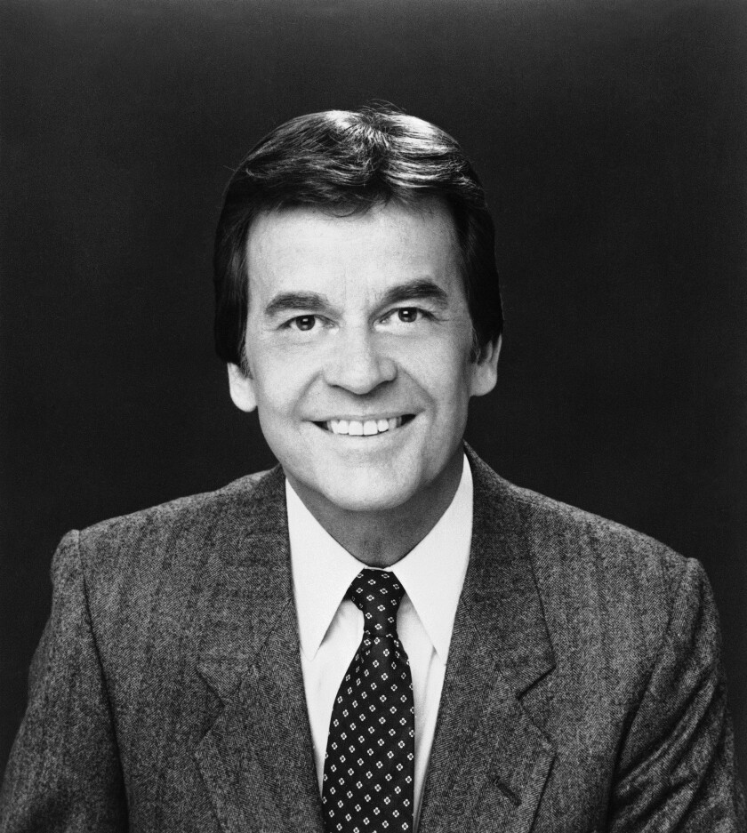 A man with dark hair smiles at the camera