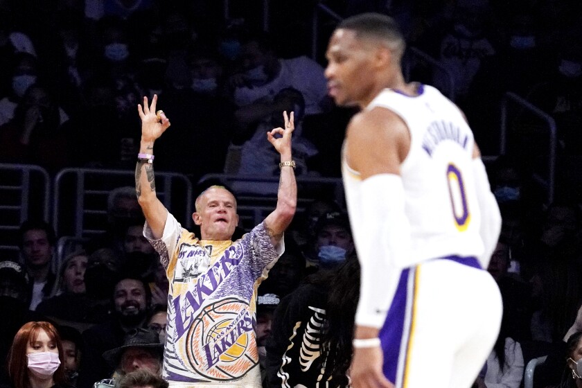 A fan in a Los Angeles Lakers t-shirt cheers on a player at a game