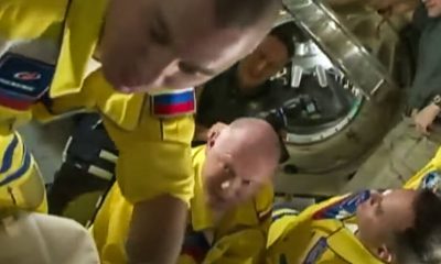 Russia’s astronauts enter the space station in yellow and blue flight suits.