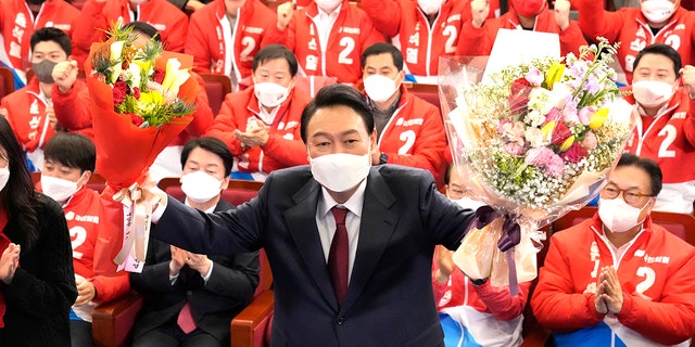 Yoon Suk Yeol, the presidential candidate of the main opposition People Power Party, who was elected South Korea's new president on Thursday, holds bouquets as he is congratulated by party's members and lawmakers at the National Assembly in Seoul, South Korea, Thursday, March 10, 2022. 