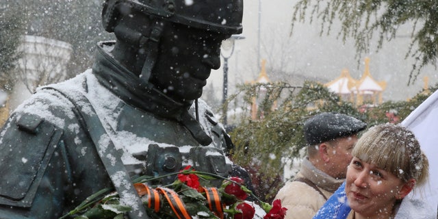 A woman looks at the monument to the so-called "polite people" or the Russian servicemen, who enhanced security during the Crimean referendum to secede from Ukraine and join Russia, during celebrations of the eighth anniversary of Russia's annexation of Crimea in Simferopol, Crimea, March 18, 2022. 