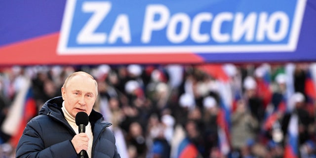 Russian President Vladimir Putin delivers a speech during a concert marking the eighth anniversary of Russia's annexation of Crimea at Luzhniki Stadium in Moscow, Russia, March 18, 2022. The banner reads: "For Russia". 