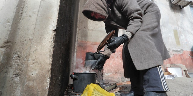 Local resident Antonina, 68, cooks soup in a street during Ukraine-Russia conflict in the besieged southern port city of Mariupol, Ukraine March 20, 2022. (REUTERS/Alexander Ermochenko)