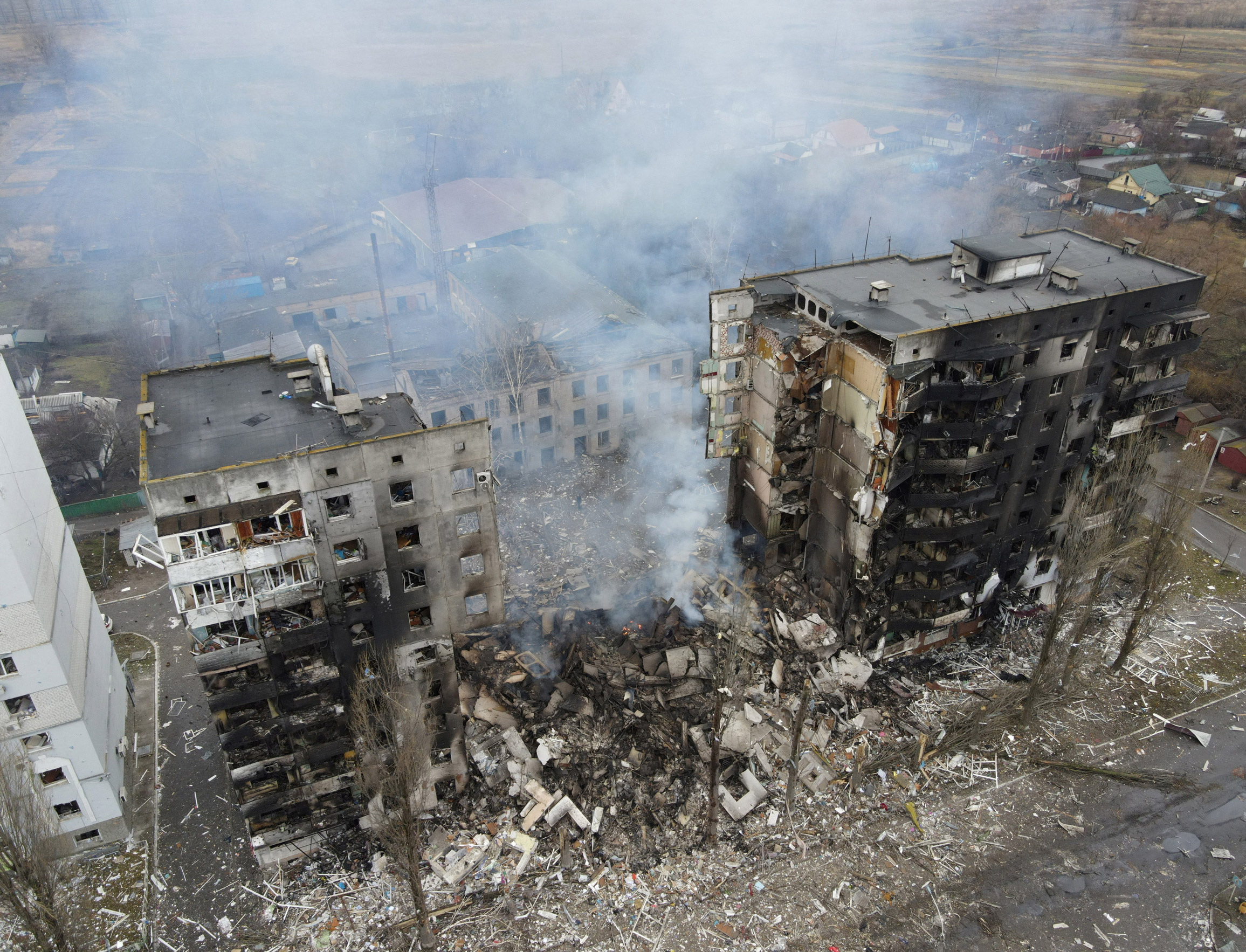 Tall apartment buildings are smouldering with large parts in rubble