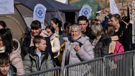 People wait Tuesday to board buses for further transportation after crossing from Ukraine into Poland at the Medyka border crossing.