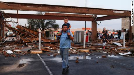 Arturo Ortega and his son Kaysen Ortega, 2, survey the damage to a shopping center after a reported tornado touched down in Round Rock, Texas, Monday. 
