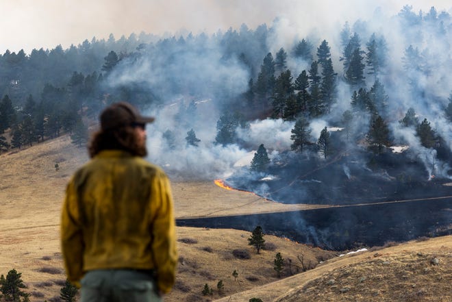 A firefighter watches as the NCAR Fire burns on March 26, 2022, in Boulder, Colorado.