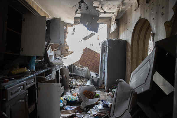 A galley-style home kitchen, with one wall broken open.