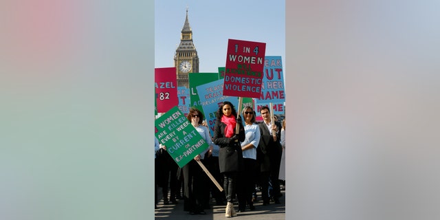 Alesha Dixon leads people holding banners during a demonstration against domestic violence 