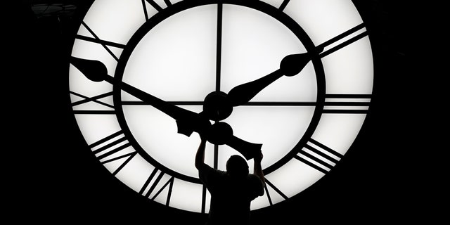 Electric Time technician Dan LaMoore puts a clock hand onto a 1000-lb., 12-foot diameter clock constructed for a resort in Vietnam, Tuesday, March 9, 2021, in Medfield, Mass. 