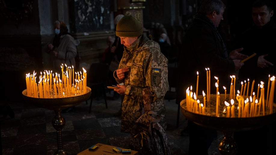 Ukrainian woman prays inside Saints Peter and Paul Garrison Church, Lviv