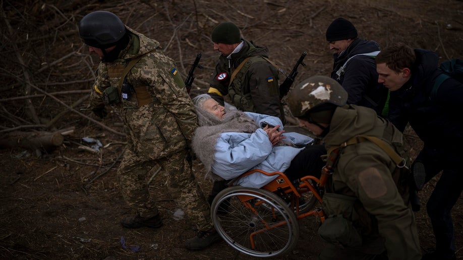 Ukrainian soldiers and militiamen carry a woman in a wheelchair