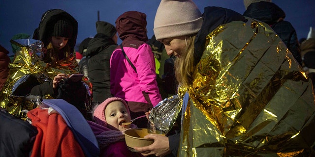 A woman feeds her daughter after fleeing Ukraine and arriving at the border crossing in Medyka, Poland, Monday, March 7, 2022. (AP Photo/Visar Kryeziu)