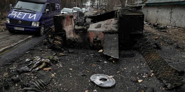 A van with the word "Children" written on it drives past a destroyed Russian tank as a convoy of vehicles evacuating civilians, leaves Irpin, on the outskirts of Kyiv, Ukraine, Wednesday, March 9, 2022. A Russian airstrike devastated a maternity hospital Wednesday in the besieged port city of Mariupol amid growing warnings from the West that Moscow's invasion is about to take a more brutal and indiscriminate turn. 