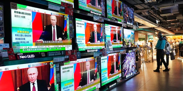 People in Hong Kong stand by TV screens broadcasting the news that Russian troops have launched an attack on Ukraine, Feb. 24, 2022.