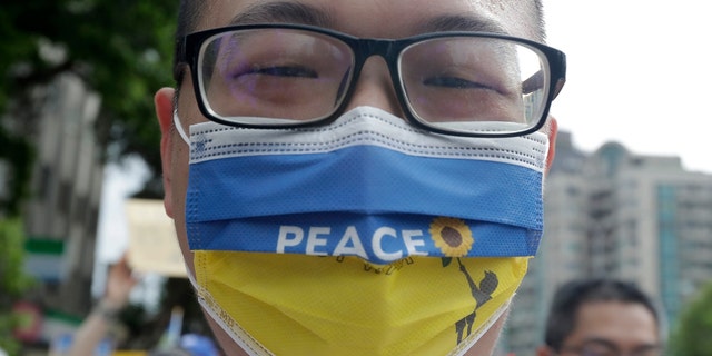 A Taiwanese man wears a Ukraine national flag-patterned mask with slogan to protest against the invasion of Russia in solidarity with the Ukrainian people during a march in Taipei, Taiwan, Sunday, March 13, 2022. (AP Photo/Chiang Ying-ying)