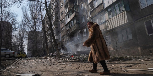 A woman walks past a burning apartment building after shelling in Mariupol, Ukraine, Sunday, March 13, 2022.