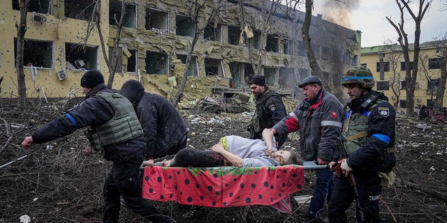 Ukrainian emergency employees and volunteers carry an injured pregnant woman from a maternity hospital damaged by shelling in Mariupol, Ukraine, on March 9, 2022. (AP Photo/Evgeniy Maloletka)