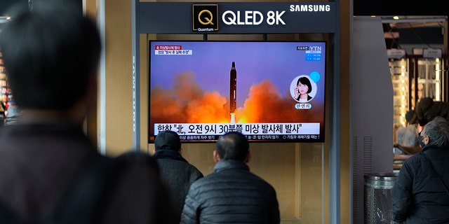 People watch a TV screen showing a news program reporting about North Korea's missile with file footage, at a train station in Seoul, South Korea, Wednesday, March 16, 2022.