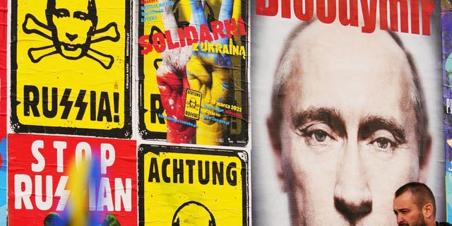 A man walks past a wall with posters depicting Russian President Vladimir Putin in Warsaw, Poland, on Thursday, March 24, 2022. Ukraine President Volodymr Zelenskyy called on people worldwide to gather in public Thursday to show support for his embattled country as he prepared to address U.S. President Biden and other NATO leaders gathered in Brussels on the one-month anniversary of the Russian invasion. 