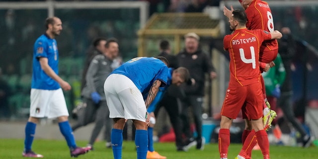 North Macedonia players celebrate as Italy players reacts after their team's elimination at the end of the World Cup qualifying play-off soccer match between Italy and North Macedonia, at Renzo Barbera stadium, in Palermo, Italy, Thursday, March 24, 2022. North Macedonia won 1-0.