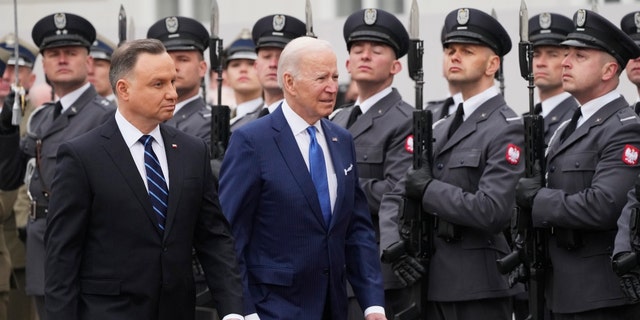 President Biden, center, and Polish President Andrzej Duda walk past an honor guard during a military welcome ceremony at the Presidential Palace in Warsaw, Poland, Saturday, March 26, 2022.