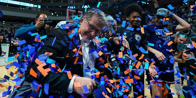 Connecticut head coach Geno Auriemma celebrates with players after defeating NC State in double overtime in the East Regional final college basketball game of the NCAA women's tournament, Monday, March 28, 2022, in Bridgeport, Conn.