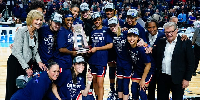 Connecticut players hold up the East Region championship trophy after defeating NC State in the East Regional final college basketball game of the NCAA women's tournament, Monday, March 28, 2022, in Bridgeport, Conn.